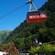 An aerial tram ascends from a station at the bottom of the mountain