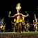 Polynesian dancers shimmy, all holding a ti leaf in each hand and wearing traditional garb