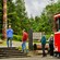 Passengers stepping out of a trolley car into a forest containing totem poles