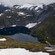 A seaplane flying over a mountainous landscape with a glacial lake near its summit