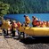 A group disembarks from a large inflatable raft onto a sandy shore at waters edge