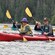 A man and a woman wearing life jackets paddle together in a kayak