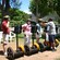 Un guía turístico ayuda a una Visitante a ajustarse el casco junto a otros tres participantes del recorrido en Segway