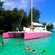 A catamaran moored in a cove as people snorkel in the water while others stand on the deck
