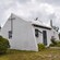 Una capilla con una cruz de madera cerca de árboles y arbustos