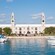 A marina full of boats near a building with 2 clock towers