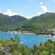 A heavily forested shoreline curves around a bay with boats and a pier