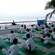 Facing a yoga instructor, Guests sit on yoga mats by the ocean and make the lotus yoga pose