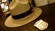 Un sombrero de campaña con una correa de cuero labrada alrededor del ala sobre una mesa con una placa de guardaparques