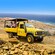 Land Rover Defenders carrying passengers across rocky terrain overlooking the ocean