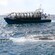 A tour boat rides alongside a broached submarine