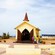 People standing outside of the open doors of a chapel and a bus in the distance