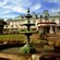 A 3 tiered water fountain adorns the front yard of a country manor