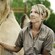 A woman wearing a zoo uniform stands next to a camel