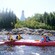 People wearing life vests kayaking along the water by a lighthouse