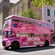 A double decker bus driving passengers down a street past the Imperial Theatre