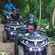 People wearing helmets riding ATVs through a wooded area