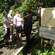 A tour group leans against a railing in a forest while a forest ranger points to a map board
