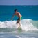 Teenage boy stands on a surf board in a wave