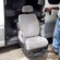 A guide poses next to a retractable chair, which is extended from the open side door of a van