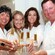 3 women and a man in lab coats smile as they hold bottles of custom made perfume and cologne