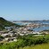 A ridge line overlooking a waterfront community with boats and small islands in the distance