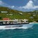 A boat called the Virgin Breeze sails past a tall resort building near the shore