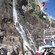 A catamaran cruising close to a steep mountainside with a cascading waterfall