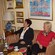 2 women sit at a coffee table with waffles on it, listening to another woman talking