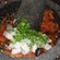 Salsa ingredients in molcajete bowl being ground by a pestle