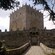 A cobblestone bridge leads to the iron front door of a square medieval castle