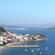 A mix of big and small buildings cover the coast next to an inlet with boats