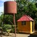 Vegetation surrounds a small water tank and a shack made from corrugated metal sheets
