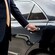 A professional driver in a suit opening the rear door of a luxury sedan