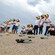 A group of children in visors releasing sea turtle hatchlings on a sandy beach
