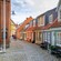 A cobblestone street in Aalborg, Denmark, lined with historic buildings and wooden benches