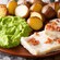 A plate filled with traditional Norwegian food including mashed peas, roasted potatoes and fish topped with pieces of bacon
