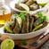 A dish of stuffed grape leaves garnished with lime wedges and parsley on a wooden table