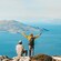Two hikers on a rocky summit of Akramitis Mountain in Rhodes, Greece, overlooking the Aegean Sea