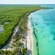 KUZÁ Ultimate Theme Park in Cozumel, Mexico, featuring a tropical beach with umbrellas and thatched roof gathering places