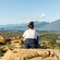 A woman sitting on top of a hill overlooking a body of water at Yellow Hill	