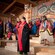Native performers in traditional clothing in front of a carved mural and totem poles at Saxman Native Village