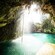 A cenote with a waterfall cascading into the water viewed from inside a cave