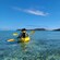 Two people kayaking on serene waters with the coastline in the distance