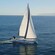 Two people standing on the deck of a sailboat as it sails along the ocean