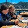 Two girls wearing wetsuits while sitting at a table and looking at nature photography near Santa Catalina Island, California