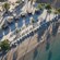 An aerial view of a private beach with palapas, picnic tables, palm trees and lounge chairs