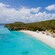 A beach along the shores of Curaçao featuring lounge chairs and thatch umbrellas