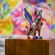 A painted wood carving of a mythical creature, mounted on a wood block