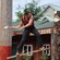 A lumberjack standing on a board suspended above the ground while chopping a tree trunk